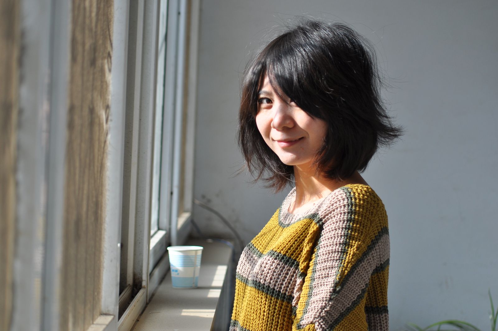 15 Elegant Italian Bob Haircut Ideas for a Sophisticated Look Young woman with a bob hairstyle smiling while standing by a window indoors