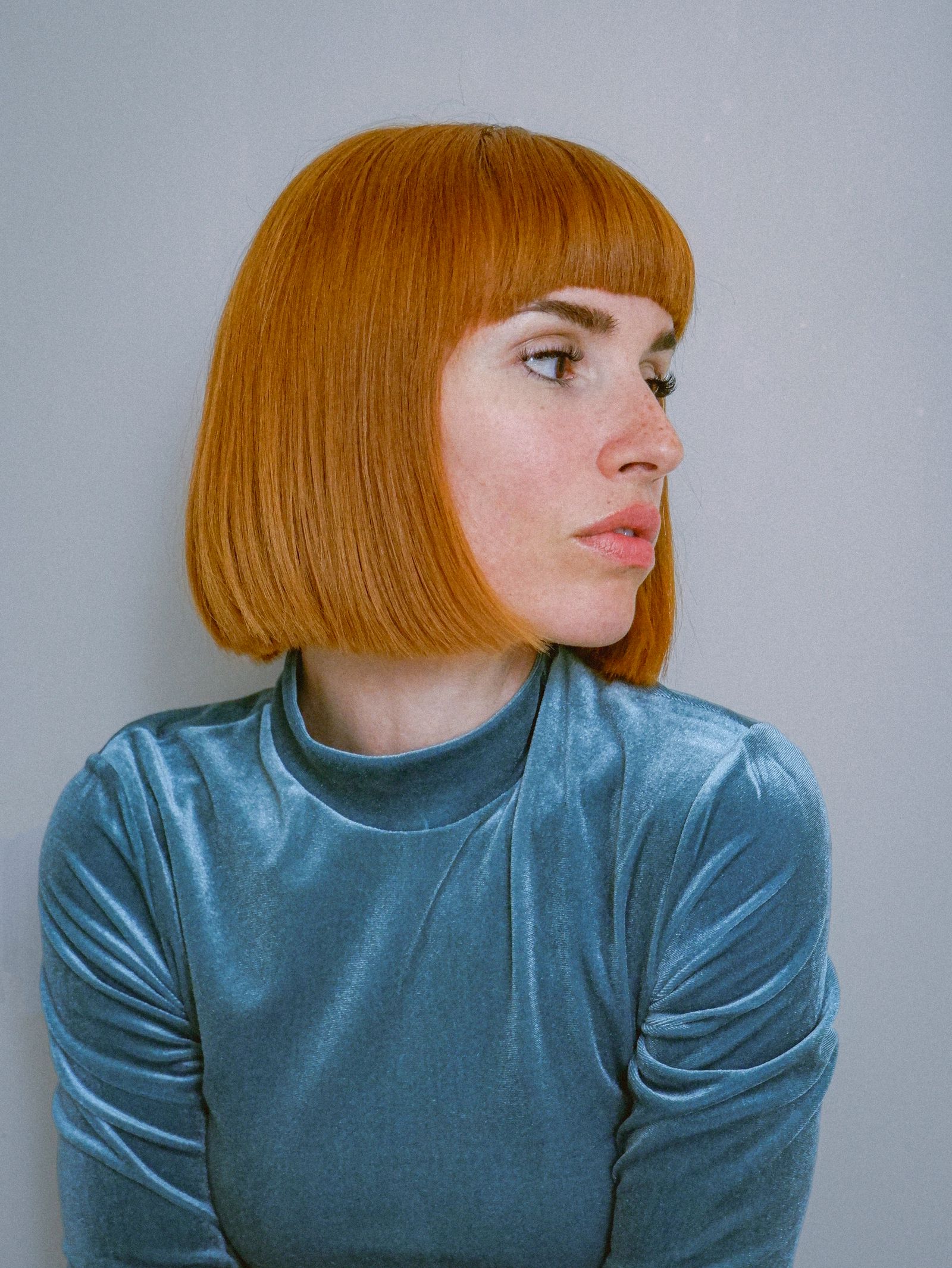 15 Trendy Bixie Haircut Ideas You Need to Try in 2026 Woman with a copper bixie bob haircut in a blue velvet top, looking over her shoulder