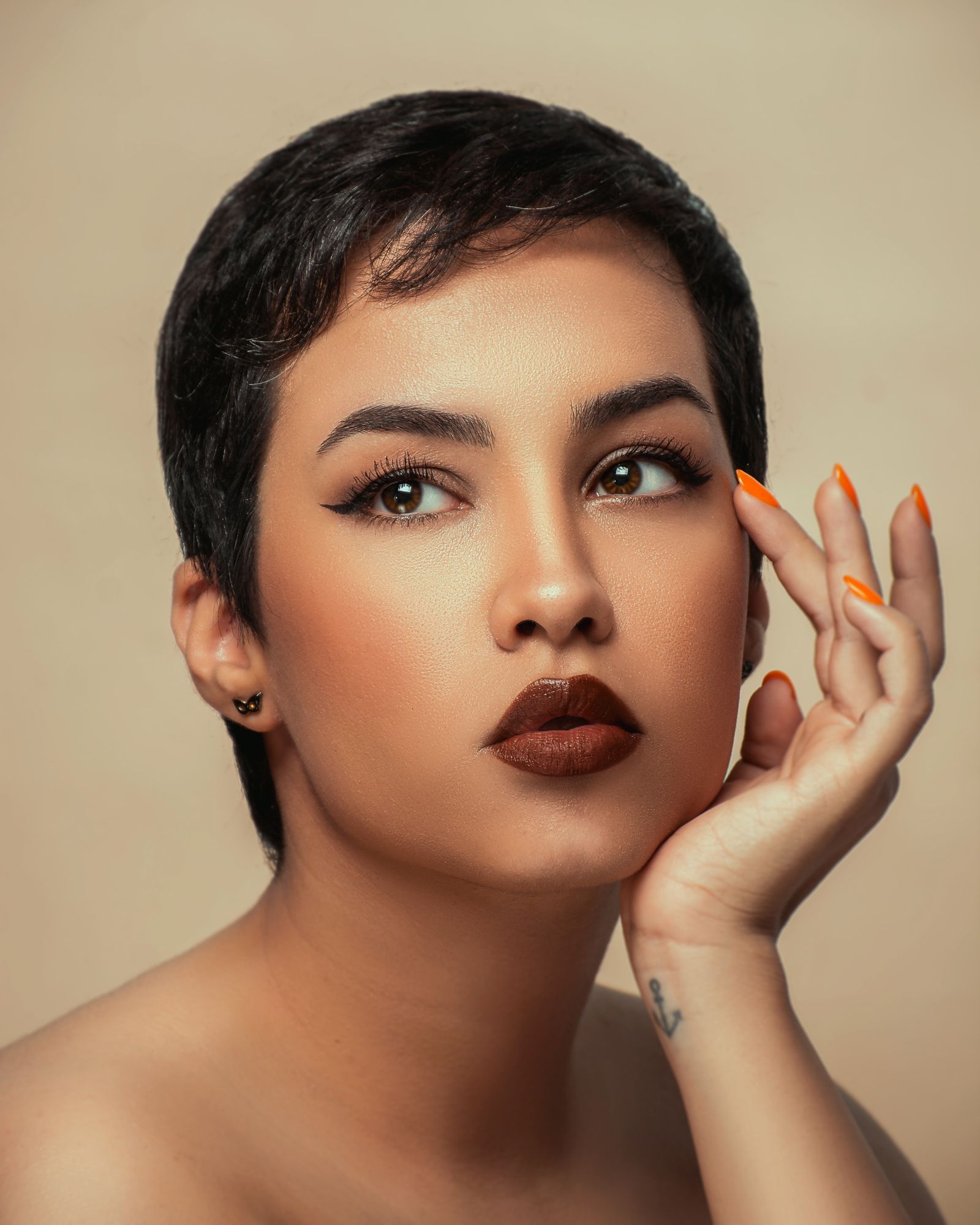 15 Trendy Bixie Haircut Ideas You Need to Try in 2026 Studio portrait of a brunette woman with a short sleek bixie haircut and bold makeup