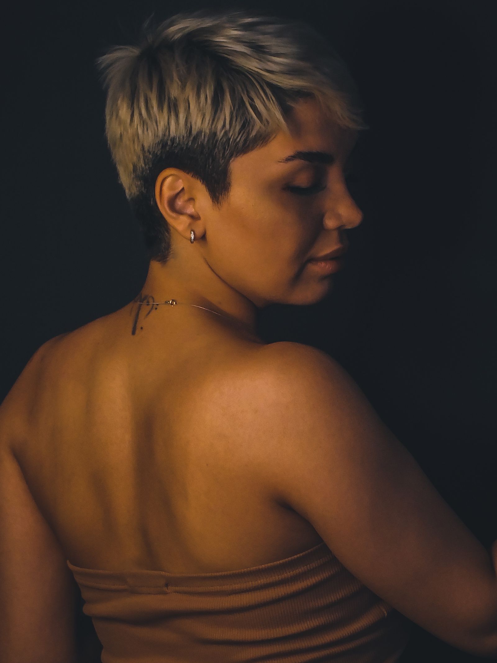 15 Trendy Bixie Haircut Ideas You Need to Try in 2026 Moody studio portrait of a woman with a short polished bixie haircut and a shoulder tattoo