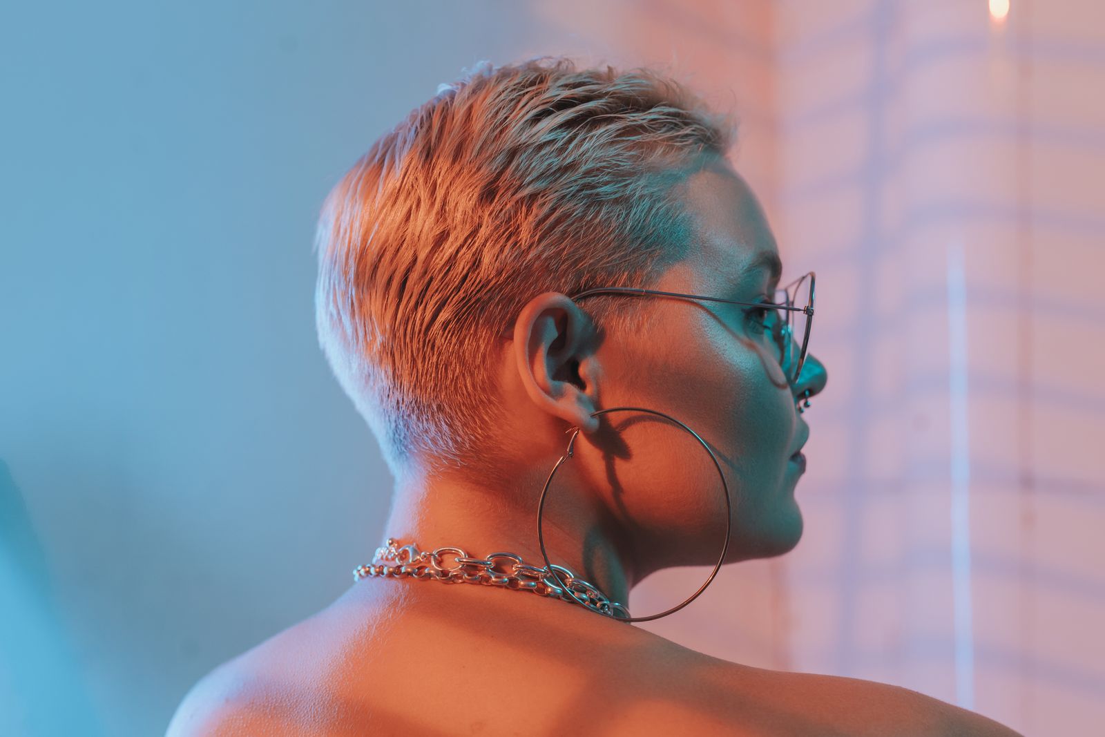 15 Trendy Bixie Haircut Ideas You Need to Try in 2026 Side profile of a woman with a short blonde bixie haircut, hoop earrings and a chain necklace