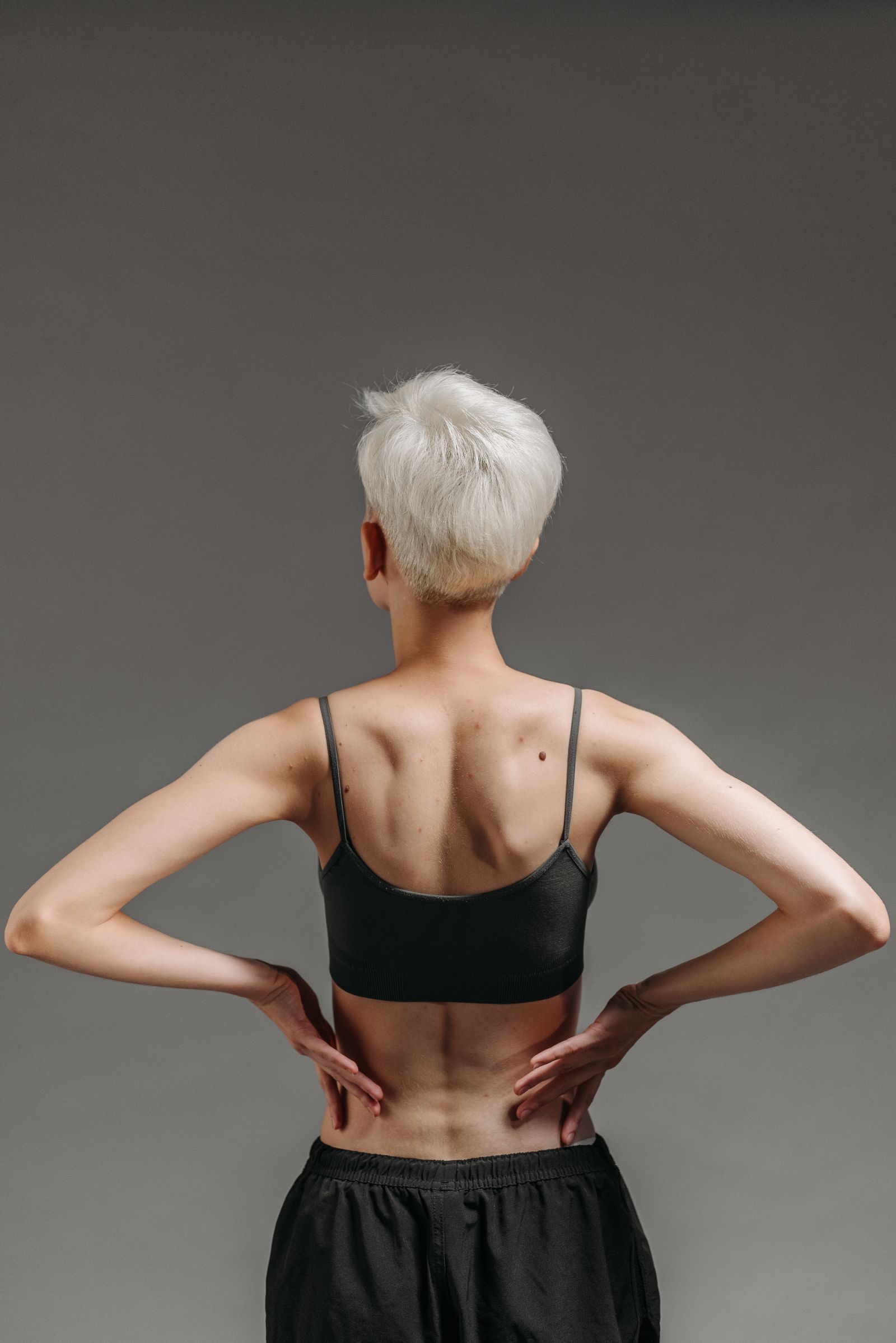 15 Trendy Bixie Haircut Ideas You Need to Try in 2026 Back view of a short white tapered bixie haircut on a woman in a sports bra