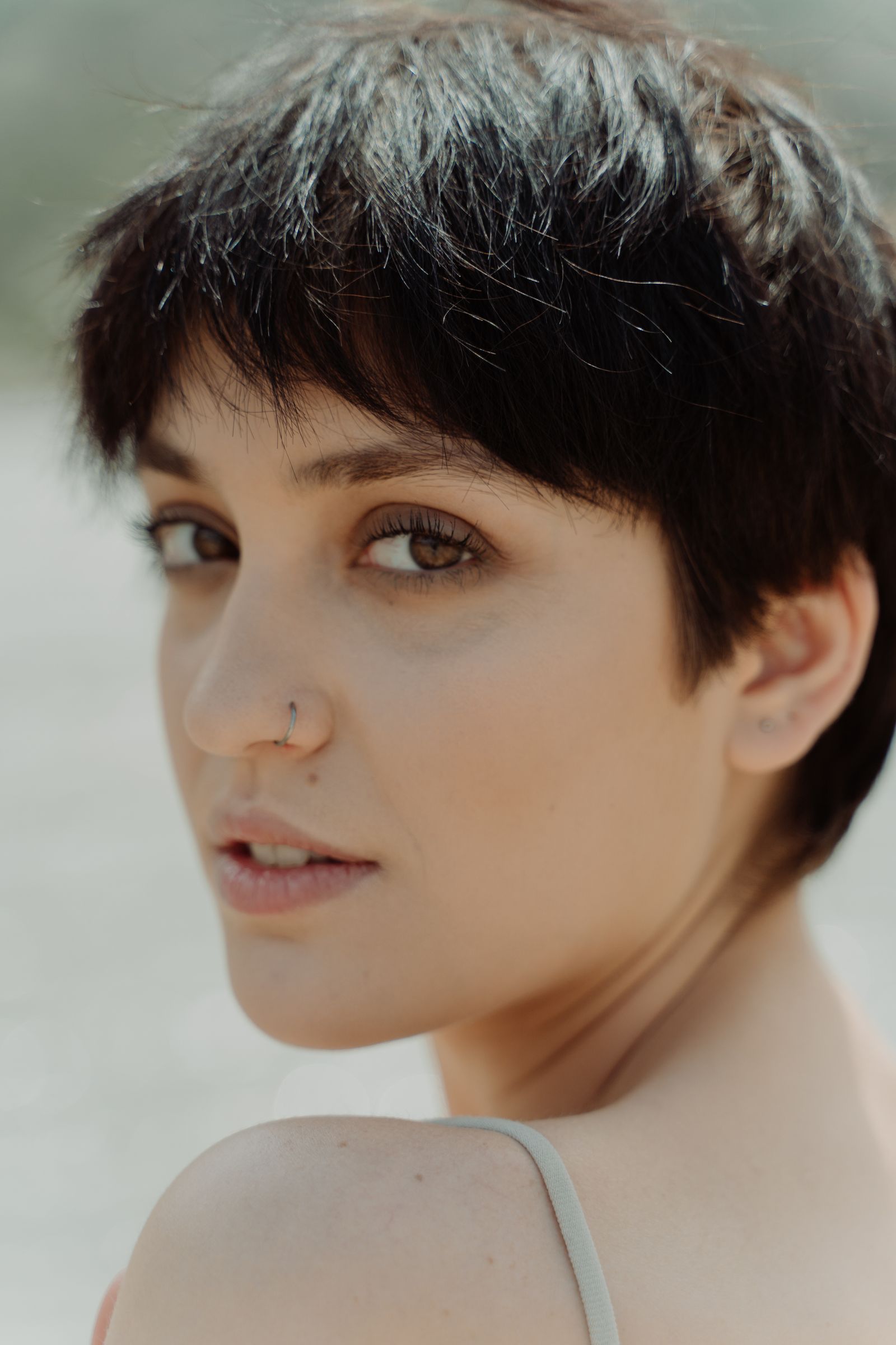 15 Trendy Bixie Haircut Ideas You Need to Try in 2026 Close-up outdoor portrait of a young woman with a short modern bixie haircut